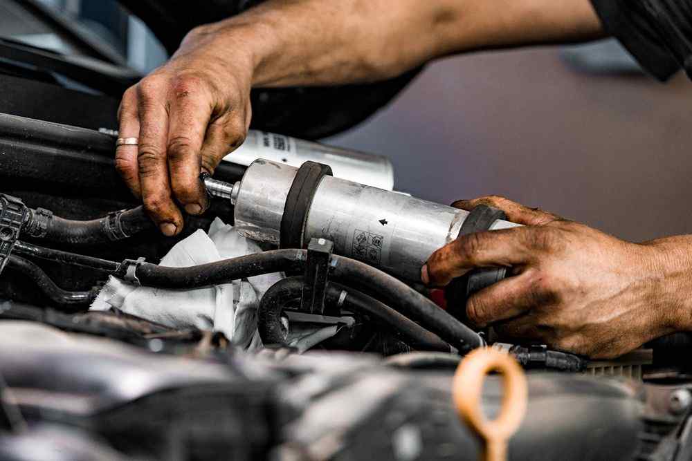 Motor bölmesinde bir araç parçasını elleriyle takan tamirci