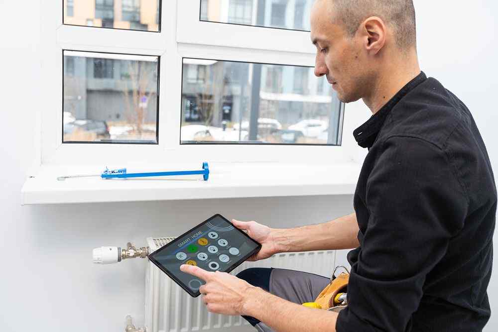 Radyatör vanasını tabletle kontrol eden bir teknisyen