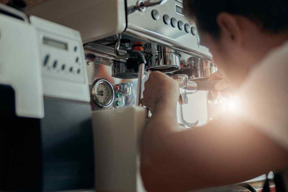 Espresso makinesinde kahve hazırlayan kişi