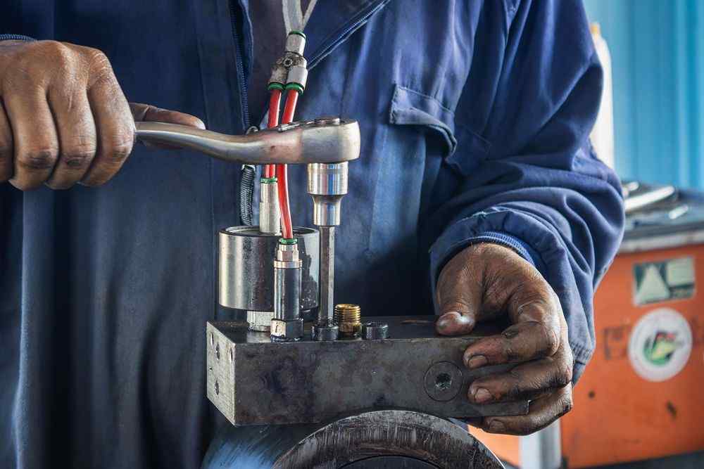 Bir işçi, metal bir parçayı anahtarla sıkıyor
