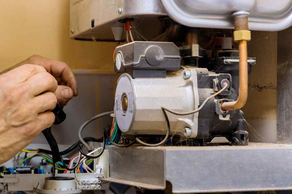 Kombi kazanının iç aksamını kontrol eden teknisyen eli