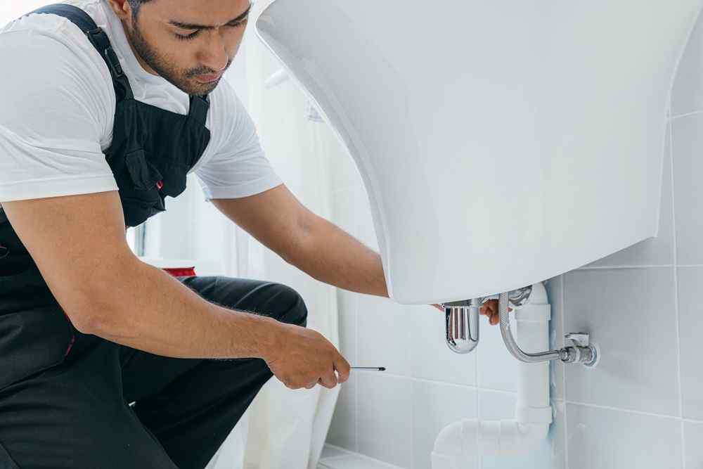 Bir tesisatçı kombi tamir ediyor.