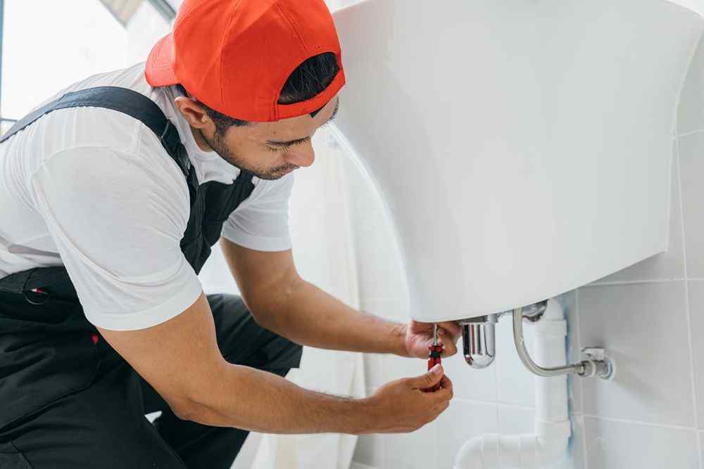 Lavabo altındaki boruyu tamir eden tesisatçı