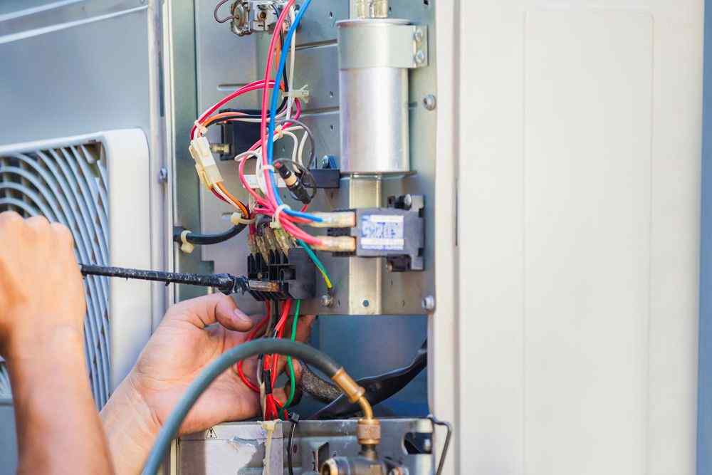 Bir teknisyen, klima ünitesinin elektrik bağlantılarını kontrol ediyor