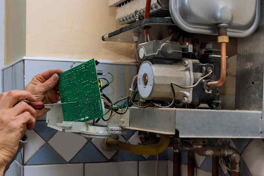 Kombi kazanının içindeki elektronik kartı tornavidayla kontrol eden Altındağ Ariston Servisi teknisyeni 