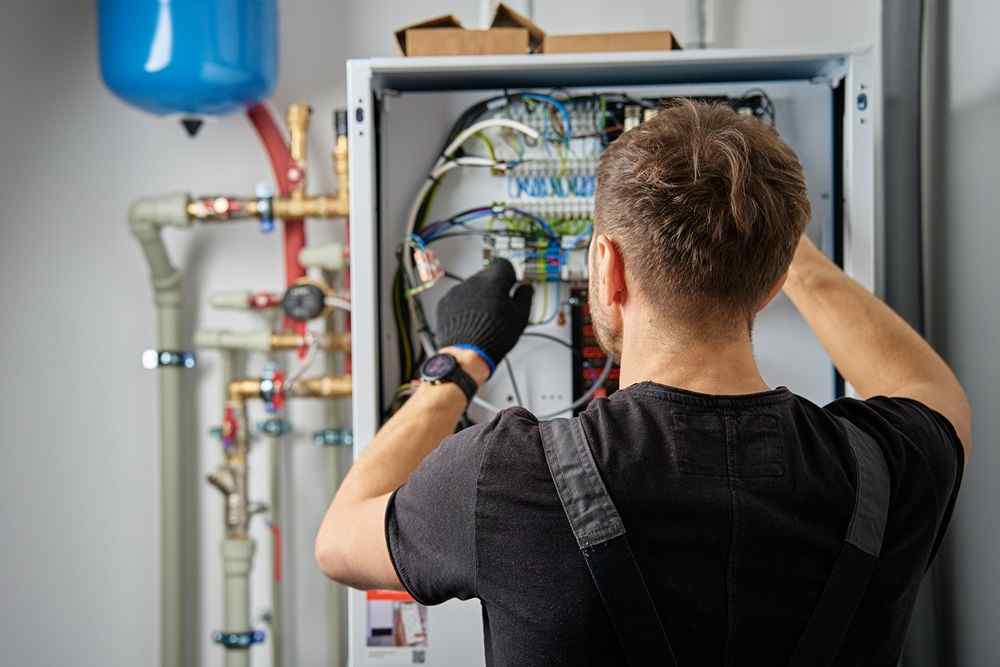 Elektrik panosunda kabloları kontrol eden teknisyen