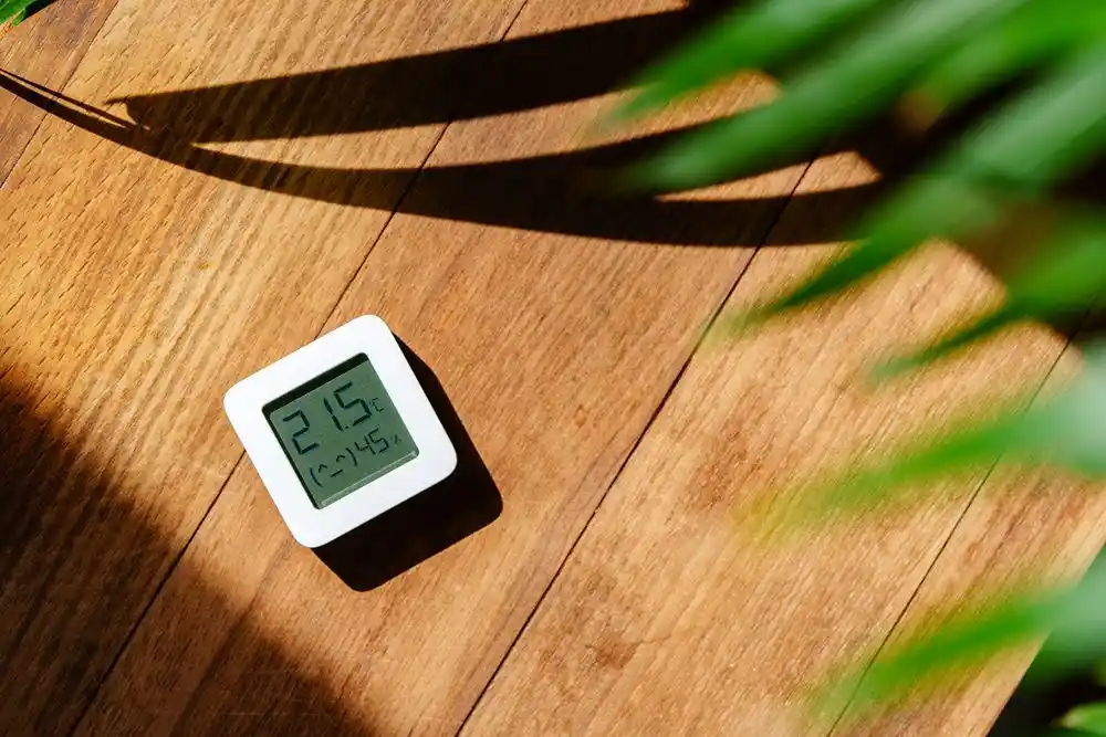 Ahşap zeminde 21,5 °C sıcaklık ve nem gösteren dijital termometre