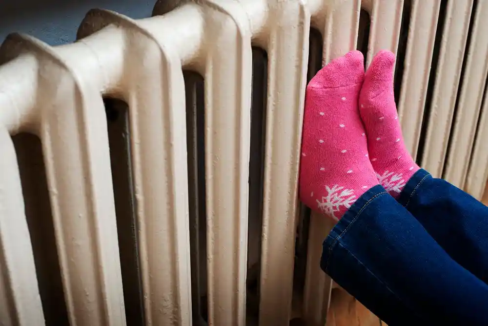Pembe çoraplı ayaklar bir kalorifer peteğinin önünde ısınıyor