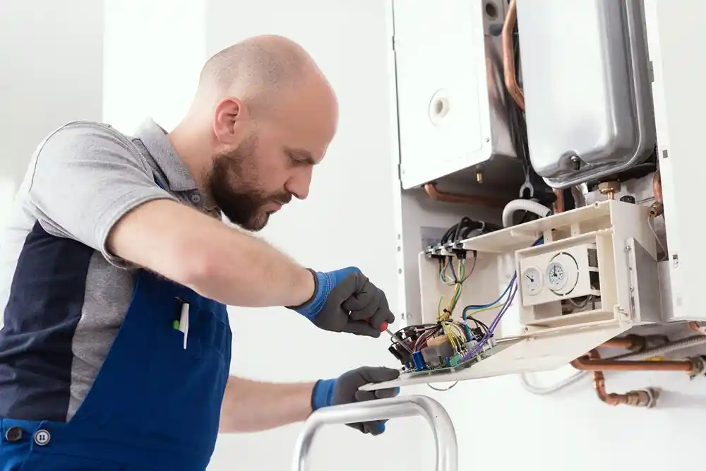 Teknisyen, açık bir kombinin elektrik bağlantılarını kontrol ediyor
