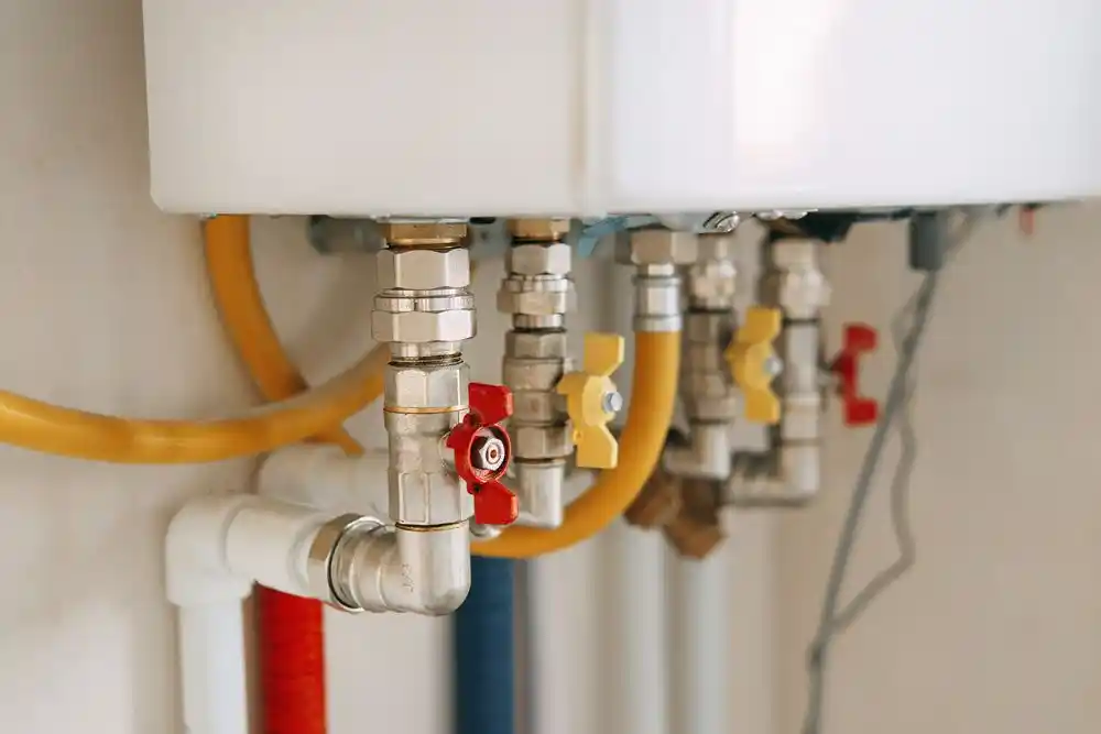 Kombinin altındaki metal borular, sarı gaz hortumları ve kırmızı-sarı vanalar