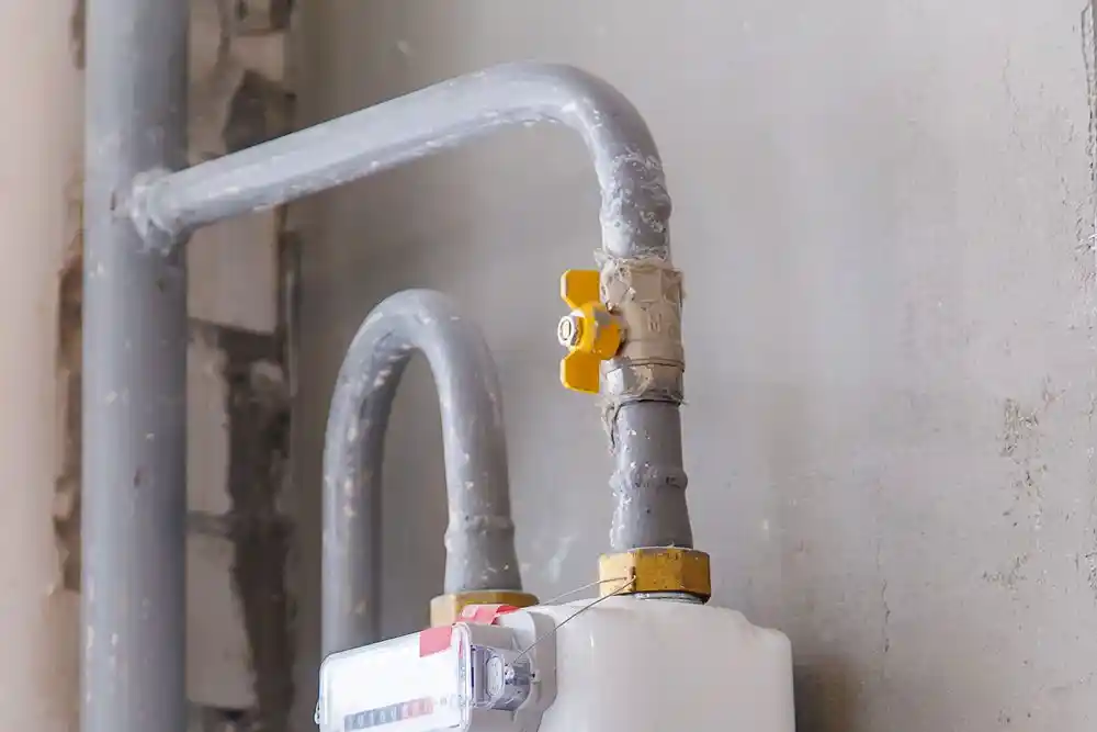 Doğalgaz sayacına bağlı gri borular ve sarı vana
