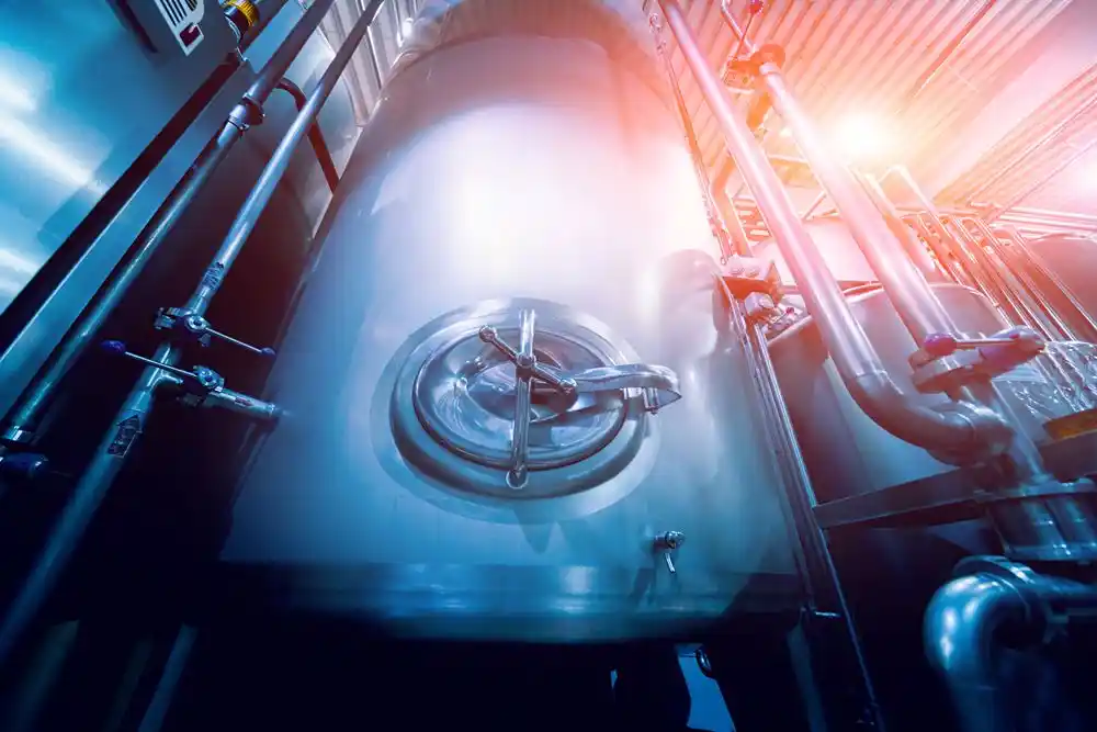 Borularla çevrili büyük bir endüstriyel metal tankın yakın planı
