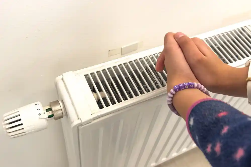 Bir kişi, kalorifer peteğinin termostatını ayarlıyor