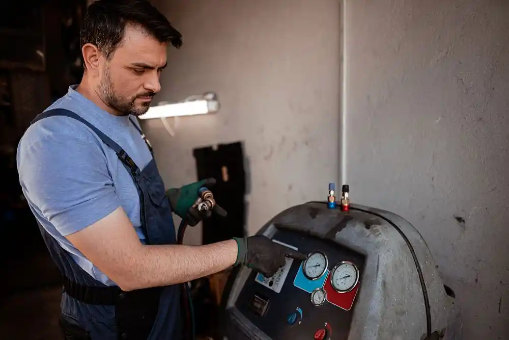 Bir teknisyen, koruyucu eldivenlerle basınç göstergeleri bulunan bir makineyi kullanıyor