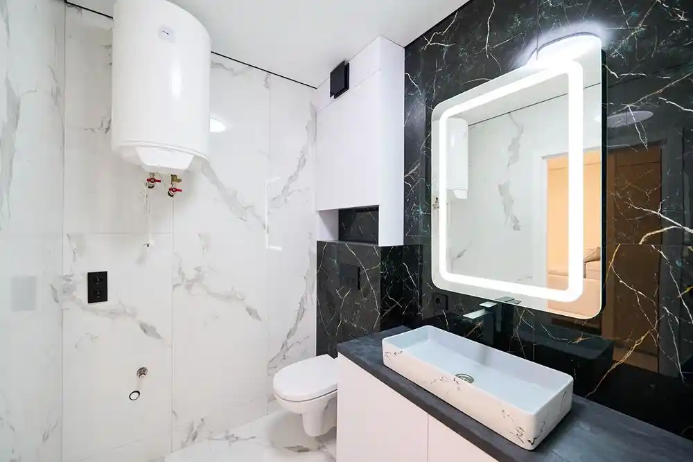 Beyaz ve siyah mermer görünümlü duvarlara sahip, lavabo ve aynalı modern banyo