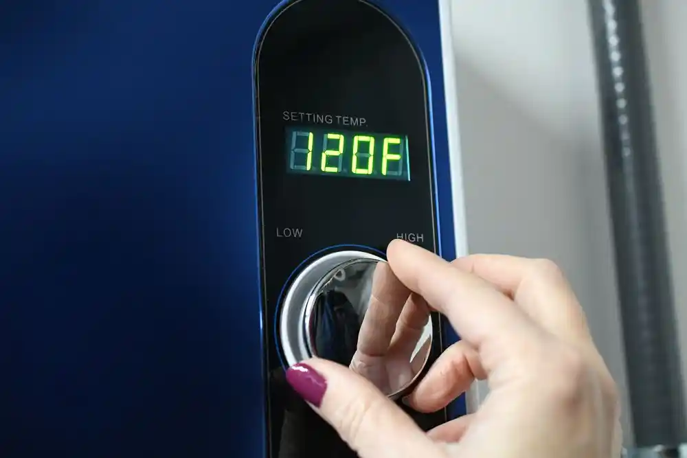 Bir el, sıcaklık ayar düğmesini çeviriyor; ekranda 120°F yazıyor