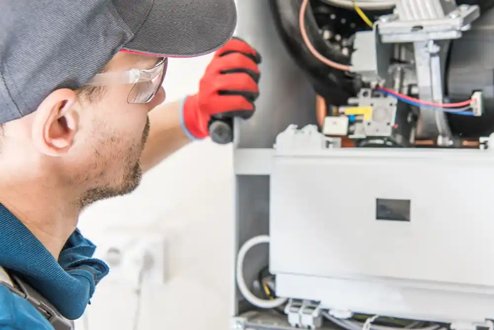 Koruyucu gözlük ve eldiven takan bir teknisyen, bir cihazın içindeki elektrik aksamını onarıyor