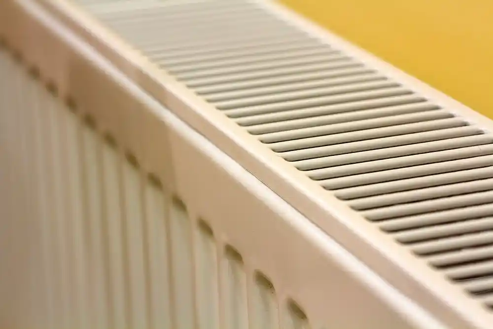 Beyaz bir panel radyatörünün üst kısmındaki havalandırma ızgarası