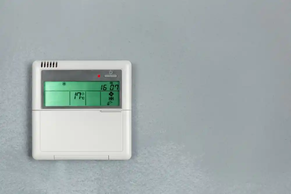 Duvara monte termostat; ekranında 17 °C sıcaklık ve 16:07 saati görülüyor