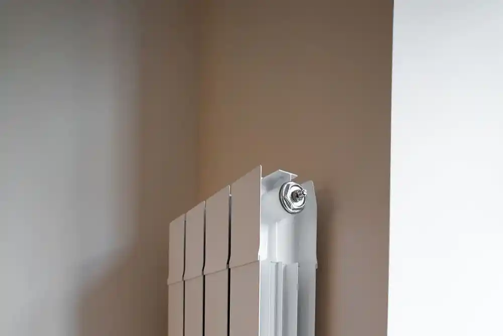 Duvara monte edilmiş beyaz panel radyatörün üst kısmı ve bağlantı aparatı