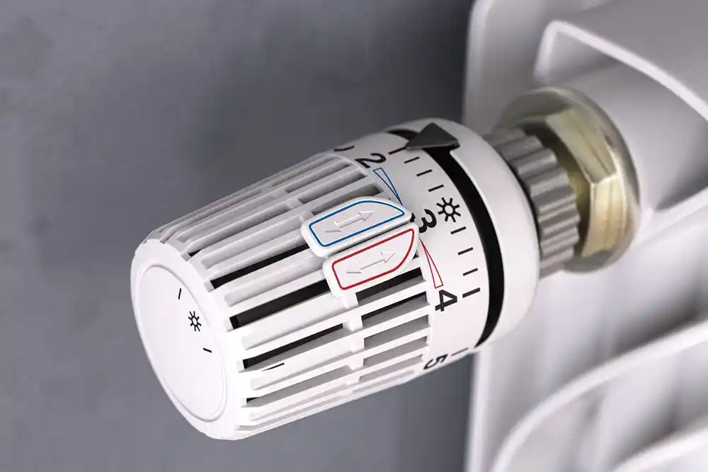 Radyatöre takılı, sıcaklık ayar düğmesi ve yön okları bulunan termostatik vana