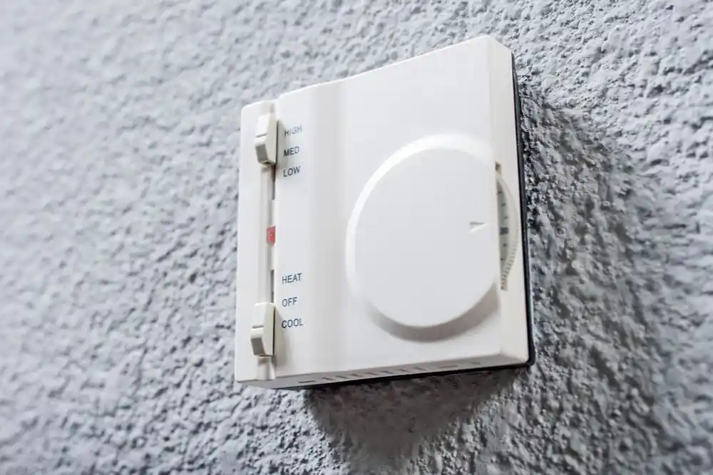 Duvara monte termostat; sıcaklık ayarı ve HEAT, OFF, COOL seçenekleri görülüyor